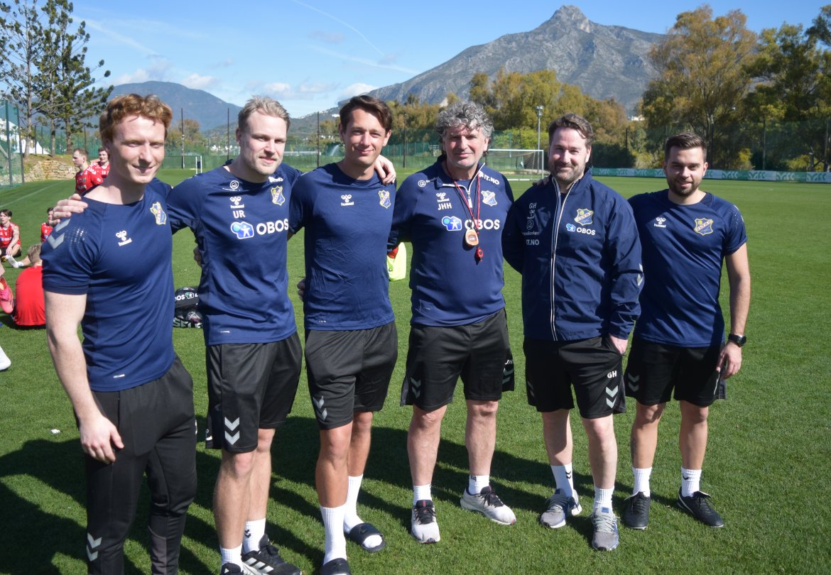 Lyns sportslige team i sesongen 2024, fra venstre fysioterapeut Fredrick Pettersen, lagleder og materialforvalgter Ulrik Rygg, keepertrener Alexander Aaser, hovedtrener Jan Halvor Halvorsen, sportssjef og assistenttrener Glenn Hartmann og analysesjef og assistenttrener Antonis Veras sine instrukser til spillerne.